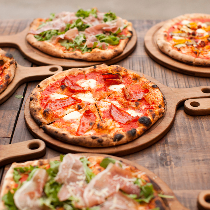 cooked pizza placed on a wooden pizza board